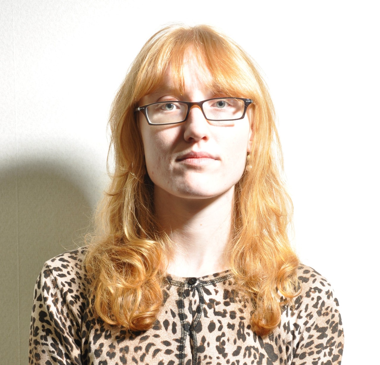 A photo of a woman wearing glasses with uneven lighting and harsh shadows on her face.