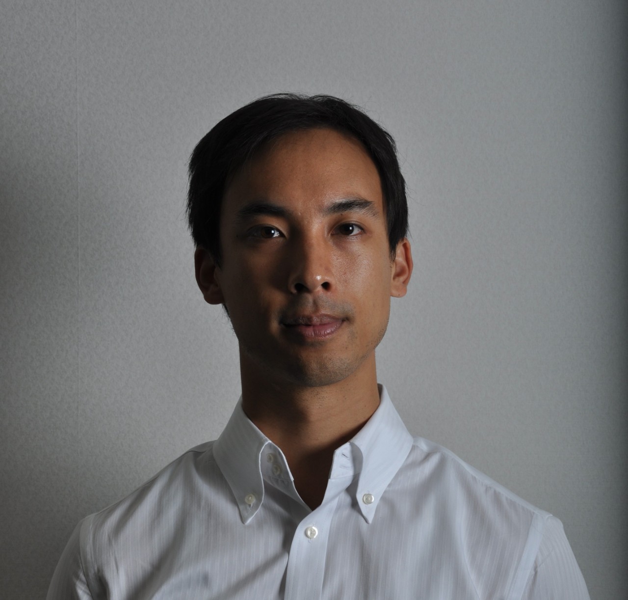  A photo of a man with uneven lighting and strong shadows across half his face.